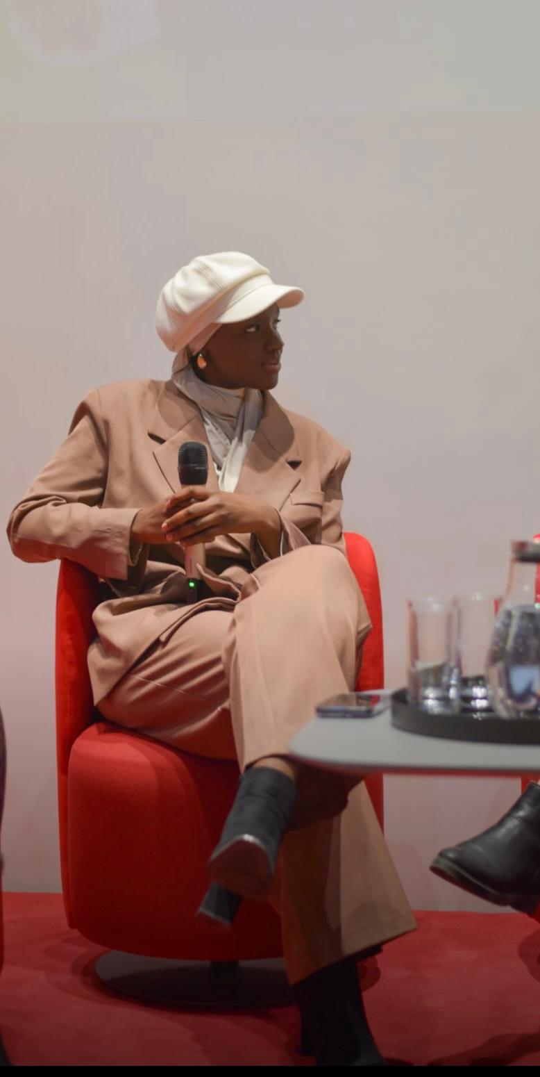 Mariame en panel de prise de parole, micro en main, lors d'une conférence